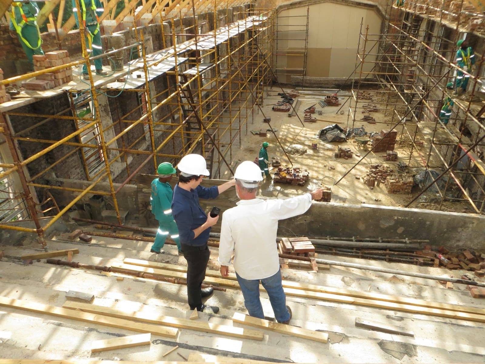 Two people in hard hats on scaffolding look over the restoration of a building in Parktown, Johannesburg